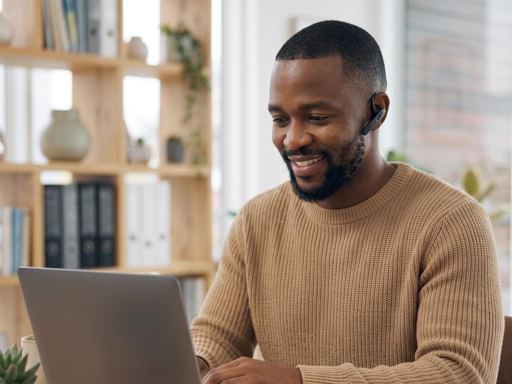Atendente da Neway com headset, sorrindo enquanto responde um cliente no computador